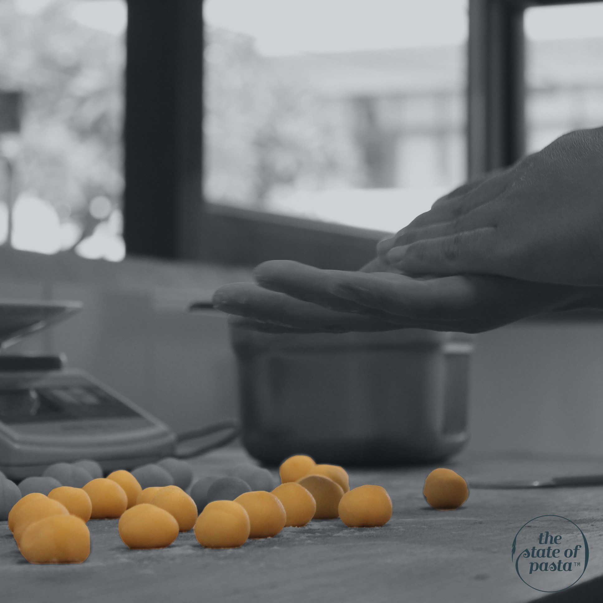 Black and white photo with a touch of color, highlighting the process of hand-rolling gnocchi one by one in The State of Pasta's open front kitchen, showcasing the artisanal preparation of this classic Italian dish.