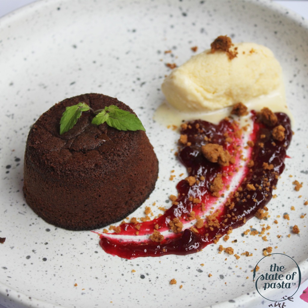 Homemade chocolate fondant made from scratch with rich local cocoa, served with creamy homemade vanilla ice cream, a zesty homemade lime crumble, and a tangy red fruits coulis.